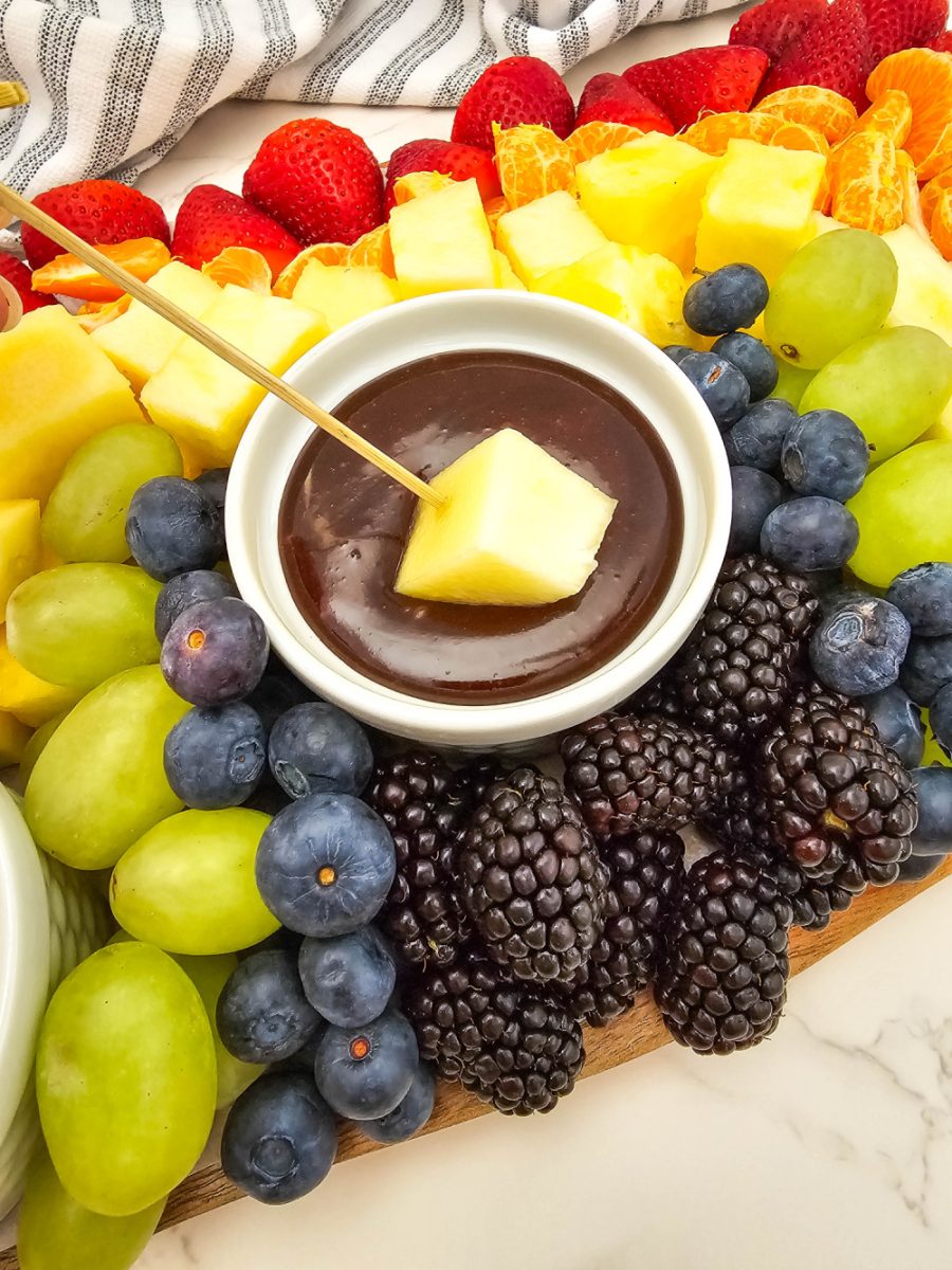 dipping pineapple chunk into chocolate sauce
